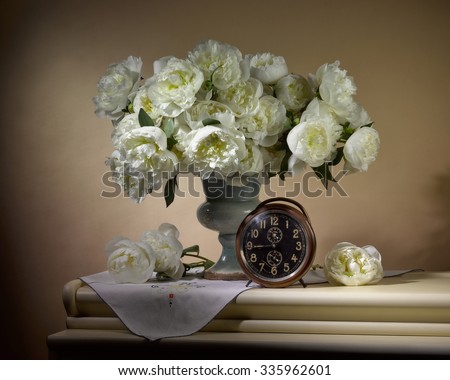 bouquet from peonies with old clock on table on beige background