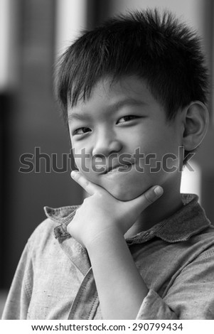 Asia kid with smiling face is posing for photo shot in black and white