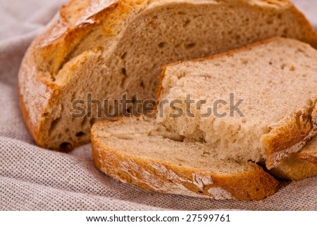 Sliced rustic rye-wheat bread loaf on the table covered with canvas tablecloth