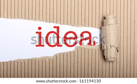Idea text on white paper with copy space and torn cardboard
