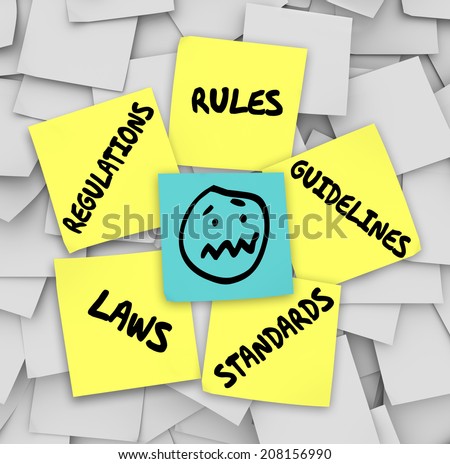 Rules, Regulations, Laws, Standards and Guidelines words on yellow sticky notes on a bulletin board  and a stressed face at the center