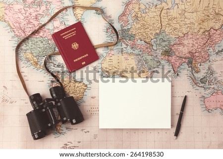 Travel planning - map with passport, notepad, pen and binoculars