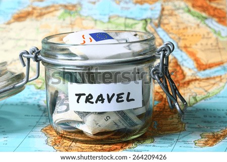 Travel budget - vacation money savings in a glass jar on world map
