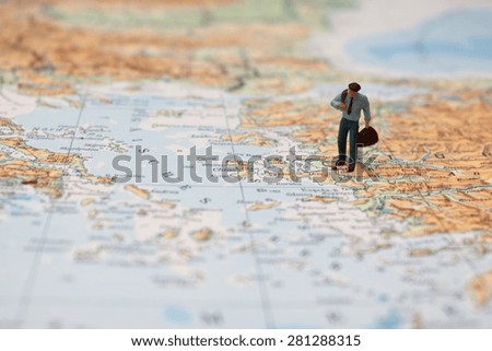 Business travel concept - Miniature traveler with suitcase on map