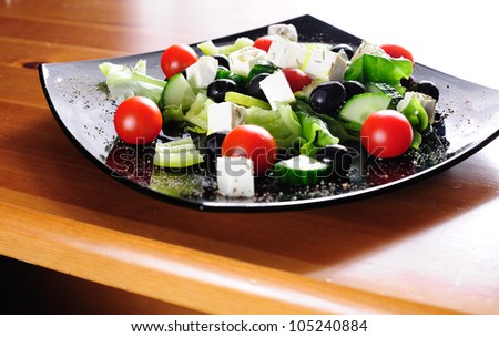 Fresh Greek salad dressed with olive oil and rosemary served on a plate