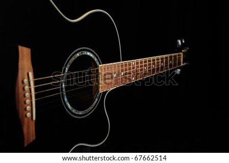 Black acoustic guitar over black background