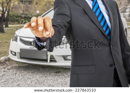 Man giving car keys with the car on background.
