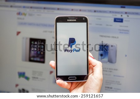 New York, USA - March 08, 2015: PayPal start page on the screen of a Samsung S3 Android smart phone and Ebay home page in browser window in the background.