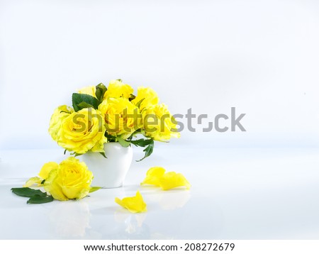 a small vase with yellow roses on the white background