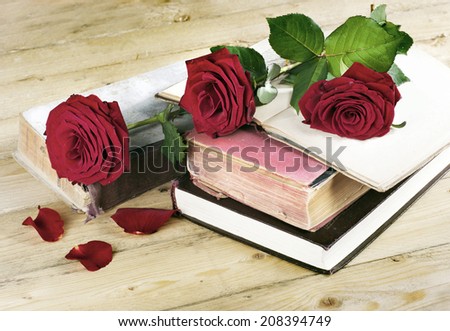 red roses on an old books on wooden desk in a vintage style
