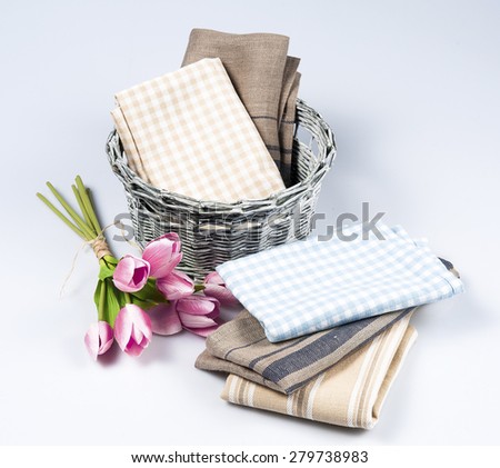 Kitchen towels and flowers in wicket basket, isolated on white