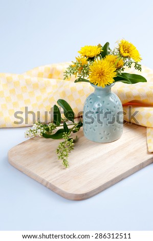 Bouquet flowers dandelion in a vase on a wooden board with napkin on a white background