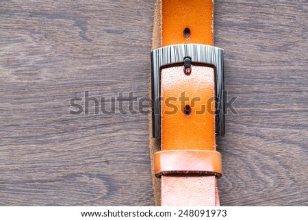 Orange leather belt on wood background