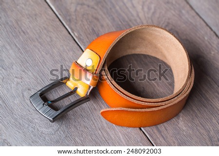 Orange leather belt on wood background