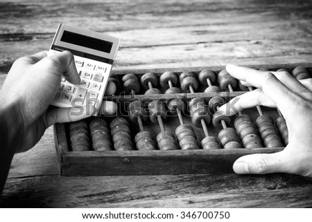 picture black & white. Man\'s hands accounting with old abacus and hold electronic calculator. picture financial concept