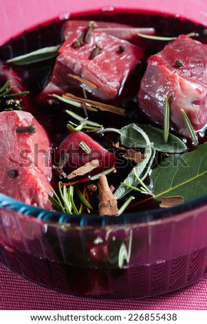 Stew meat, recipe carbonade, meat macerated in red wine and spices in a glass bowl on a pink background