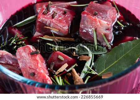 Stew meat, meat macerated in red wine and spices in a glass bowl on a pink background