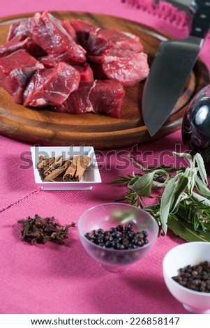 Stew meat, meat macerated in red wine and spices in a glass bowl on a pink background
