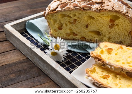 Colomba cake is a typical italian easter cake, takes this name for the form of a dove. Slices of Colomba Pasquale cake on a tray put on a wood table.