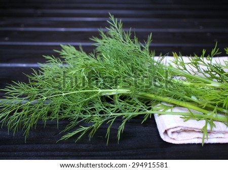 Bunch of dill on beige cotton towel on black  wood