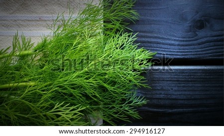 Bunch of dill on beige cotton towel on black wooden table