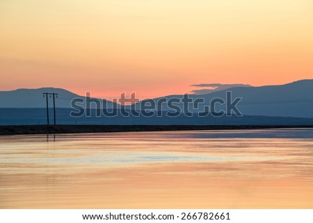 Silhouette of transmission lines crossing a body of water at sunset, McKenzie Country, New Zealand