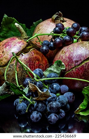 Pomegranate and wild grapes on a black background