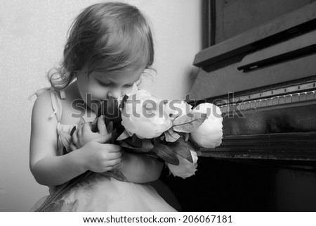 portrait of a little girl near the piano with flowers