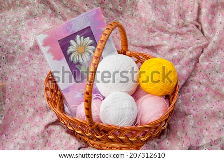 wicker basket with balls of yarn and a book on a picnic