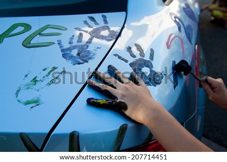 child\'s hands in paint, making a mark on the hood of the car, paint the car