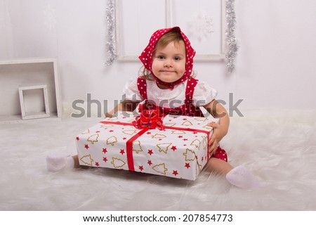 little girl in a red kerchief holding a big gift with red ribbon, holiday, new year, white background
