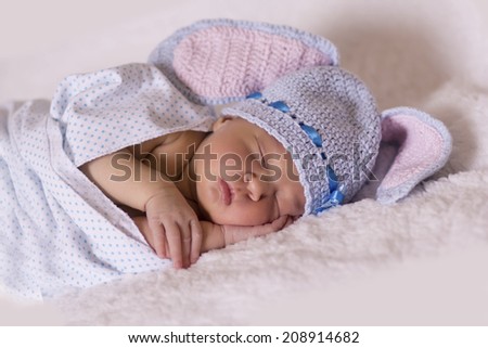 Sleeping newborn baby in knitted cap hare, five days old