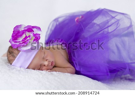 Sleeping newborn baby in a lilac dress princess, five days old