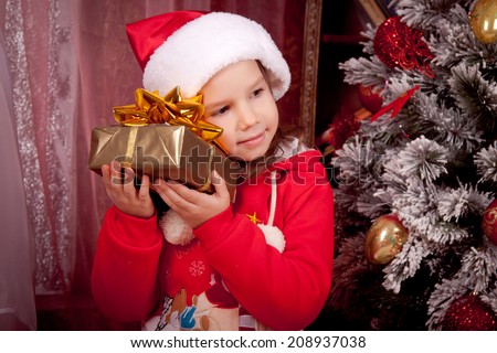 Joyful kid dressed as Santa put his ear to the present, Christmas, New Year