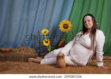 Pregnant woman in national dress drinks water from a jug, Slavic peoples, Russian and Ukrainian national style, rustic style