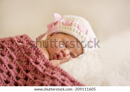 beautiful sleeping newborn baby in knitted cap under the rug, five days old