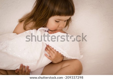 Older sister kissing his newborn sister. Beautiful little girl with a newborn baby in her arms