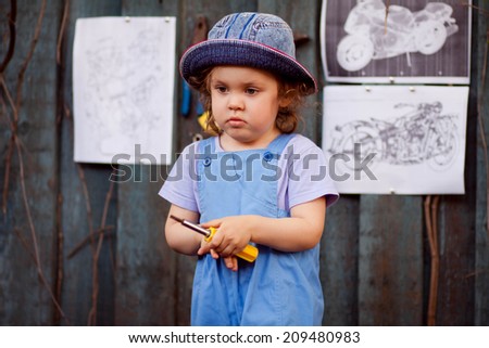 Portrait of a young child in the image of the master, the master\'s assistant in the studio, working with tools