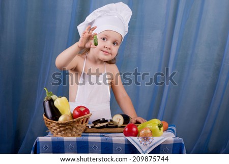 Little cook prepares healthy food, offers a small beautiful cucumber