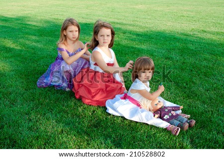Three little girls sitting on the lawn in the summer, combing each other's hair. Assistance, care, family