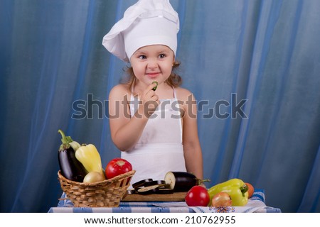 Little chef is tasting the sour cucumber, wrinkles his nose from a sour taste. Cookie in the kitchen