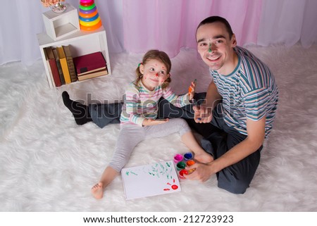 Happy father with a daughter draw finger paints, make handprints, home, indoors