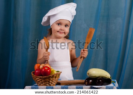 Little cook prepares healthy food, cheery kitchen boy at the table, happy kitchen boy holding a basket of vegetables