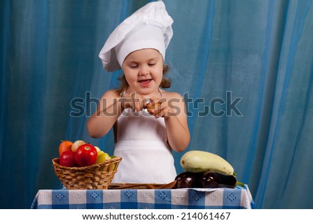Little cook prepares healthy food, cheery kitchen boy at the table, happy kitchen boy holding a basket of vegetables