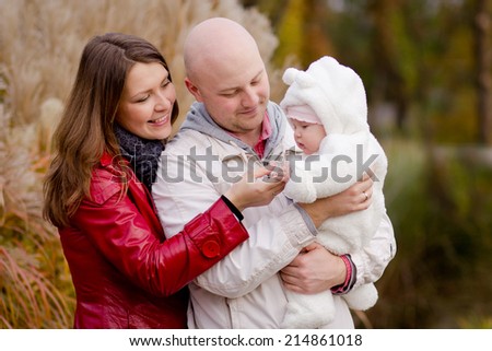 Happy family on a walk in the park. Dad, mom and baby are happy autumn weather and communication