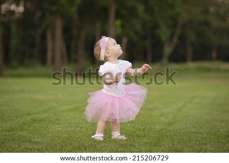 Little ballerina in the park. Baby age of 1 year in a skirt ballerina