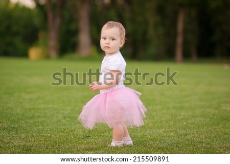 Little ballerina in the park. Baby age of 1 year in a skirt ballerina