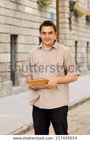 Happy student with books in hands near the school