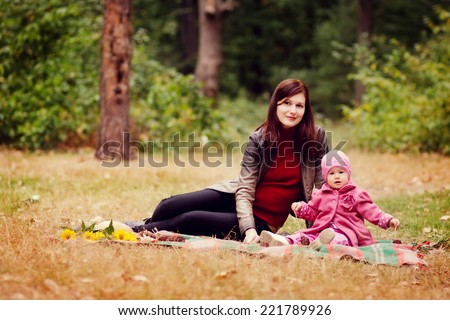Mother and daughter in autumn forest. Mother with little girl on picnic in the autumn park