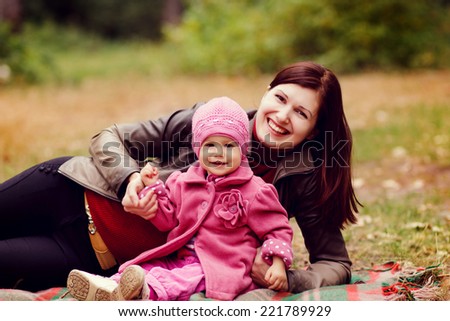 Mother and daughter in autumn forest. Mother with little girl on picnic in the autumn park